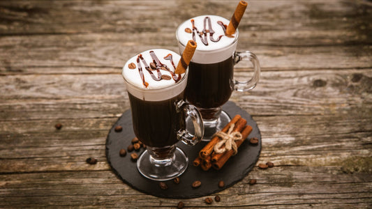 two glasses of irish coffee on a slate plate and wooden table
